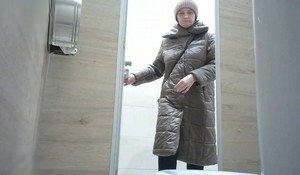 Немолодая женщина писает в туалете общего пользования
